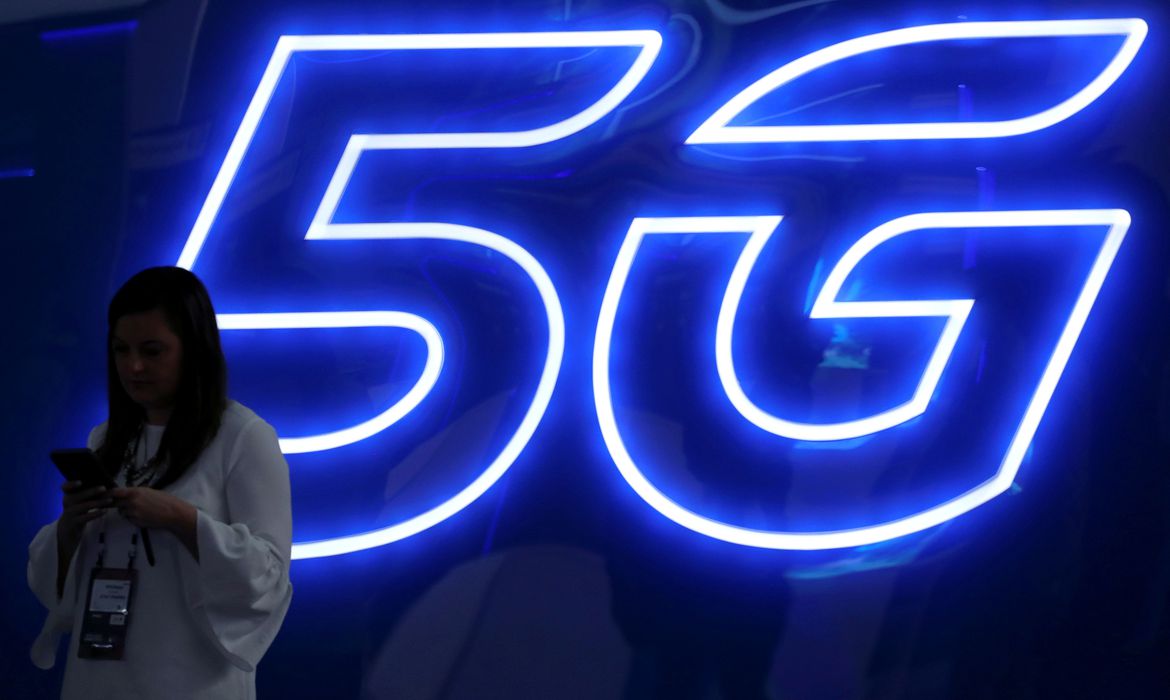 FOTO DE ARCHIVO: Una mujer mira su teléfono móvil junto a un cartel de 5G en el Mobile World Congress en Barcelona, España, 25 de febrero de 2019. REUTERS/Sergio Pérez