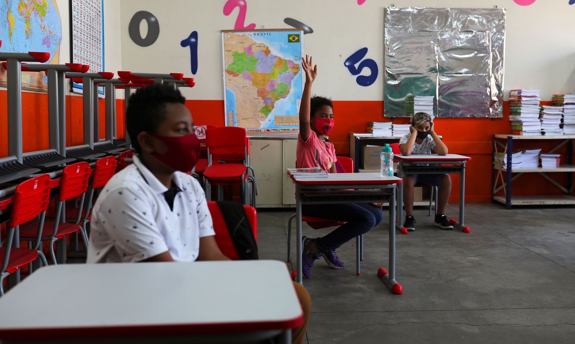 Criança levanta a mão ao lado de outros alunos em sala de aula da escola Thomaz Rodrigues Alckmin, no primeiro dia de retorno das escolas do estado de São Paulo para atividades extracurriculares em meio ao surto de coronavírus (COVID-19) em São Paulo, Brasil Outubro 7, 2020. REUTERS / Amanda Perobelli